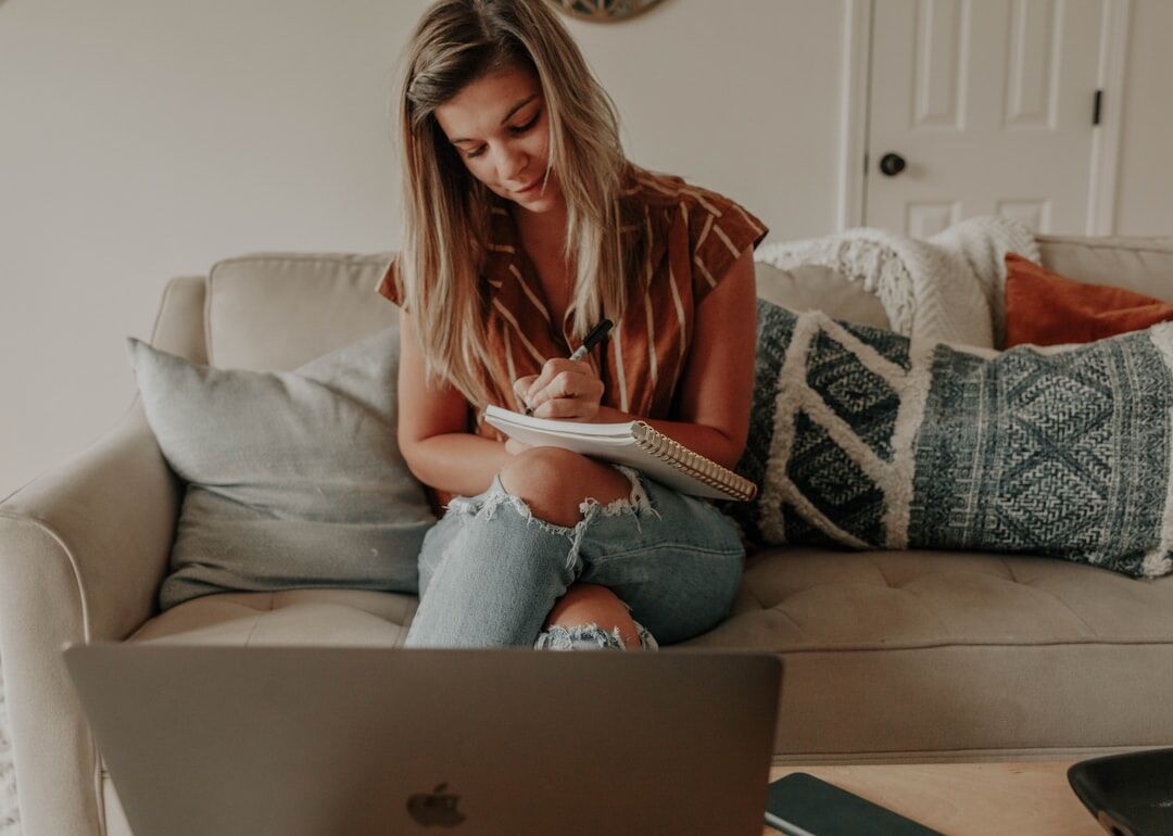 Person taking notes during an online coaching session on a laptop